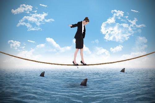 A woman HR Director walking a tightrope over shark infested waters